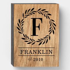 a wooden plaque with the letter f on it and an image of a laurel wreath