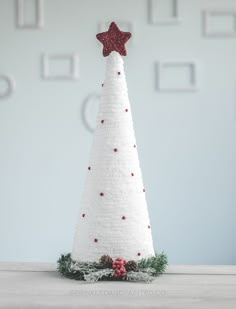 a small white christmas tree with a red star on top, sitting on a table