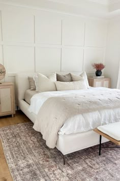 a large bed sitting on top of a wooden floor next to a white dresser and window