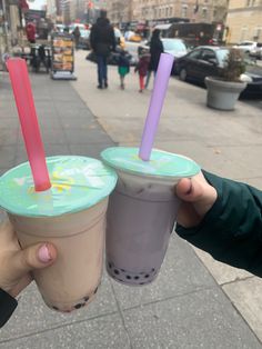 two people holding up drinks on the sidewalk