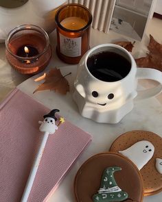 a cup of coffee and some cookies are on a table next to candlelight candles