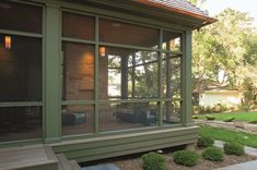 a screened in porch with green grass and trees