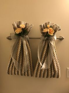 two towels hanging on a towel rack with flowers in the middle and ribbons around them