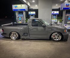 a gray truck parked in front of gas pumps