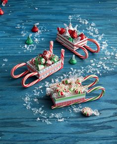 candy canes and christmas candies in miniature sleighs on blue wood