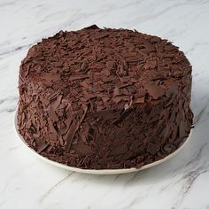 a chocolate cake sitting on top of a white plate next to a marble countertop