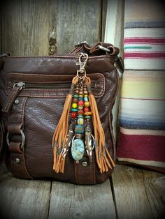 a brown leather purse sitting on top of a wooden floor next to a striped pillow