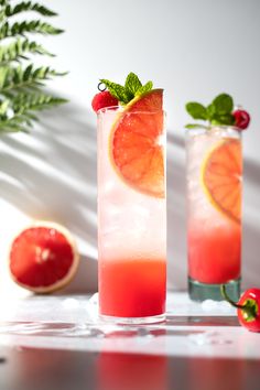 two tall glasses filled with red liquid and garnish