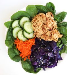 a white plate topped with lettuce, carrots and cucumbers