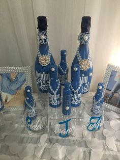 there are many blue bottles on the table with pearls around them and pictures behind them