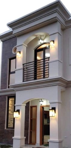 a white two story house with lights on the balcony and balconies above it