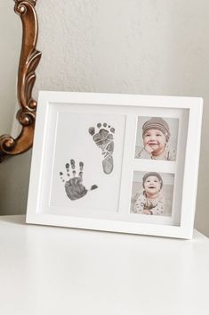 a baby's hand and foot prints are displayed in a white frame on a table