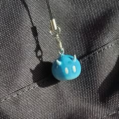 a small blue object is hanging from a black cord on a piece of fabric that has been stitched together