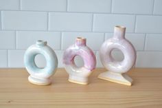 three ceramic vases sitting on top of a wooden table