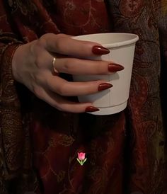 a woman's hand holding a white cup with red nail polish on her nails