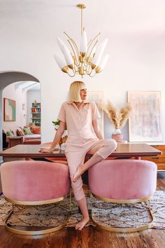 a woman sitting on top of a pink bench in front of a chandelier