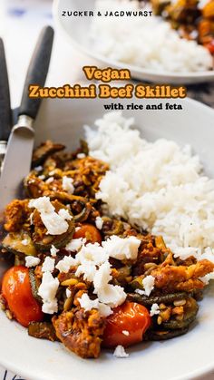 a white plate topped with meat and rice next to a knife on top of a table