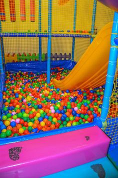 there is a ball pit with a slide in the center and lots of balls all around it