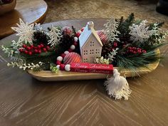 a christmas centerpiece with pine cones, ornaments and a house on a sled