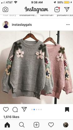 two sweaters with flowers on them hanging from a hanger in front of a white wall