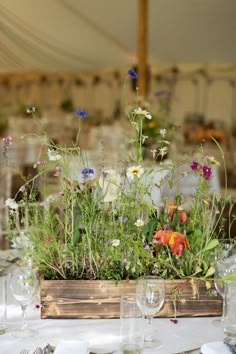 a wooden box filled with lots of flowers on top of a white table cloth covered table