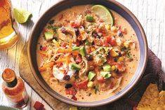 a bowl of mexican soup with tortilla chips and limes on the side