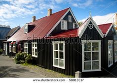 a row of black houses with red roof tops and white windows on the street in front of them