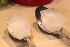 two spoons filled with ice on top of a table