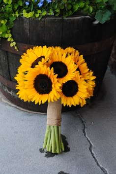 a bouquet of sunflowers tied to a wooden barrel