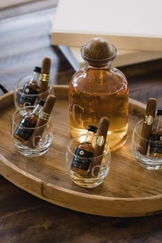 four glasses with bottles in them sitting on a wooden tray