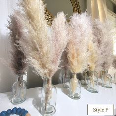 three vases with dried flowers in them sitting on a table next to a mirror