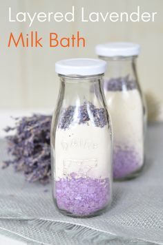 two jars filled with bath salts and lavenders on top of a cloth covered table