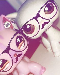 a pink pony with glasses and stars on it's face next to a white horse