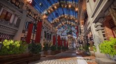 the inside of an indoor shopping mall with lots of plants and lights hanging from the ceiling