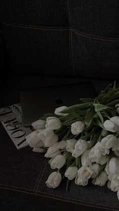 white tulips are laid out on a couch next to an open laptop computer