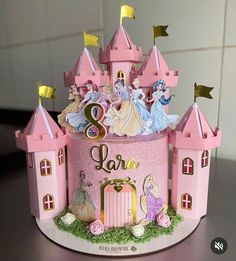 there is a pink cake with princess figures on the top and bottom tiers that say 2