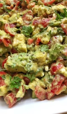 a white plate topped with guacamole and tomatoes