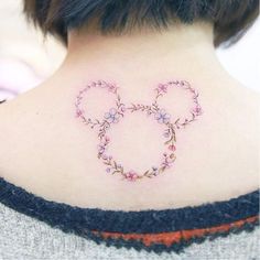 a woman with a tattoo on her back neck that has flowers in the shape of mickey ears