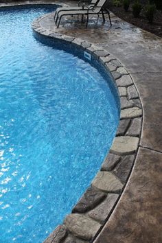 an empty swimming pool with chairs around it