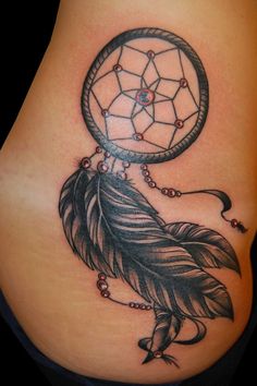 a woman's stomach with a tattoo on it that has a dream catcher and beads