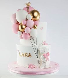 a white cake with pink and gold balloons on top