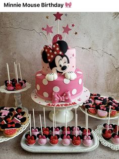 a minnie mouse birthday cake and cupcakes on a table