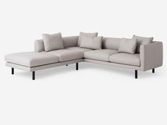 a white sectional couch with pillows on it's back and arms, facing the camera