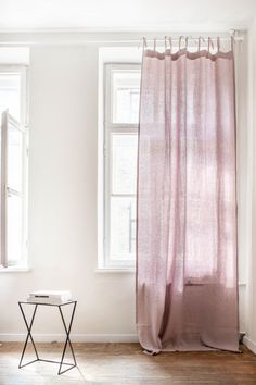 an empty room with two windows and a pink curtain