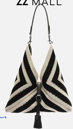 a black and white striped purse with tassels on the handles, hanging from a hook