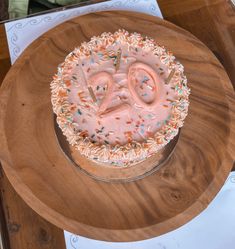 a birthday cake with sprinkles and the number twenty on it is sitting on a wooden platter