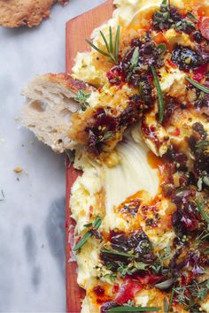 an omelet with cranberry sauce and herbs on a wooden cutting board