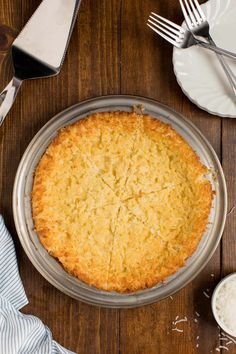 a pie sitting on top of a wooden table next to silverware and utensils