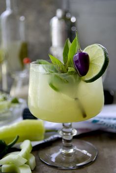 a cocktail with lime, cucumber and an olive garnish