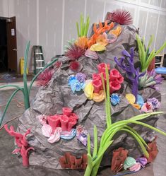 a rock covered in fake flowers and plants